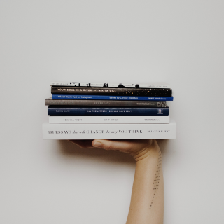 Фотография руки, держащей стопку книг